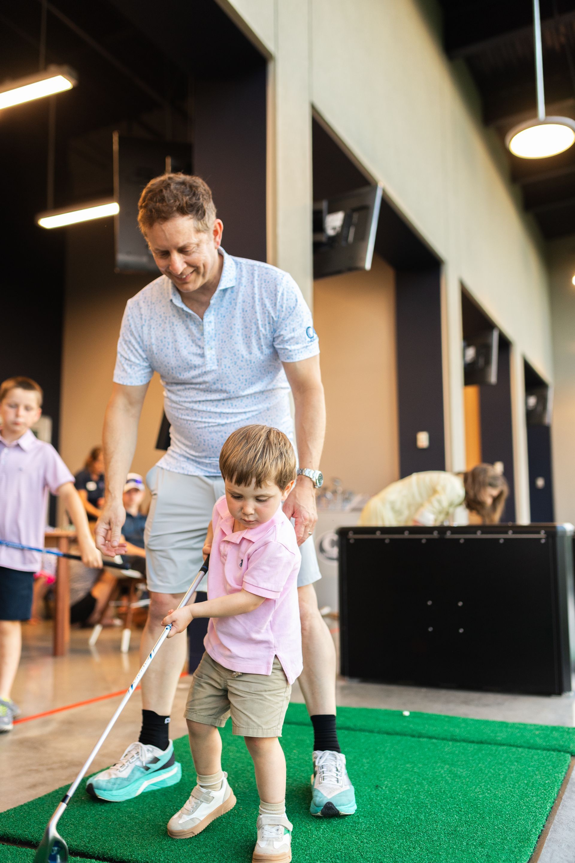 A man is teaching a young boy how to play golf.