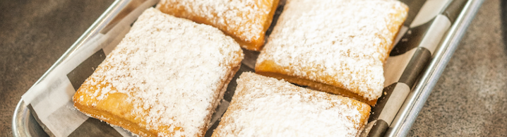 Powdered sugar-dusted square pastries in a tray lined with parchment paper