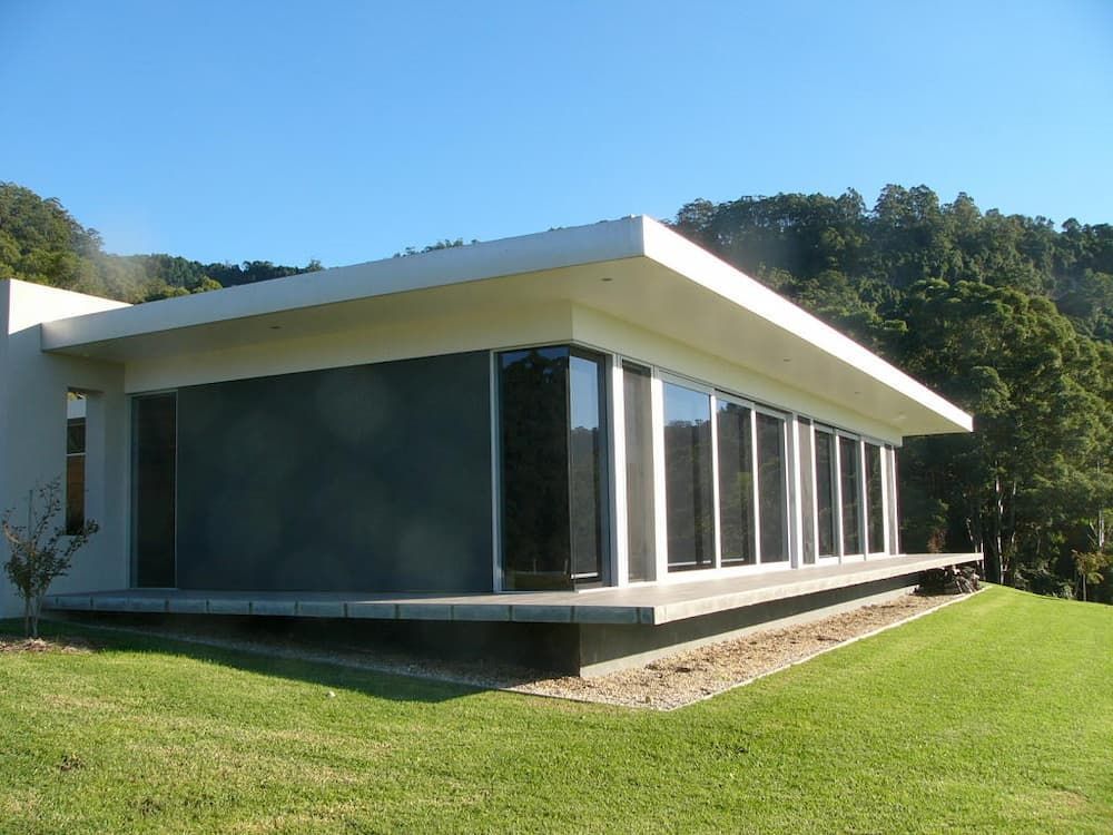 A House With A Lot Of Windows Is Sitting On Top Of A Lush Green Hillside — South Coast Glass In South Nowra, NSW