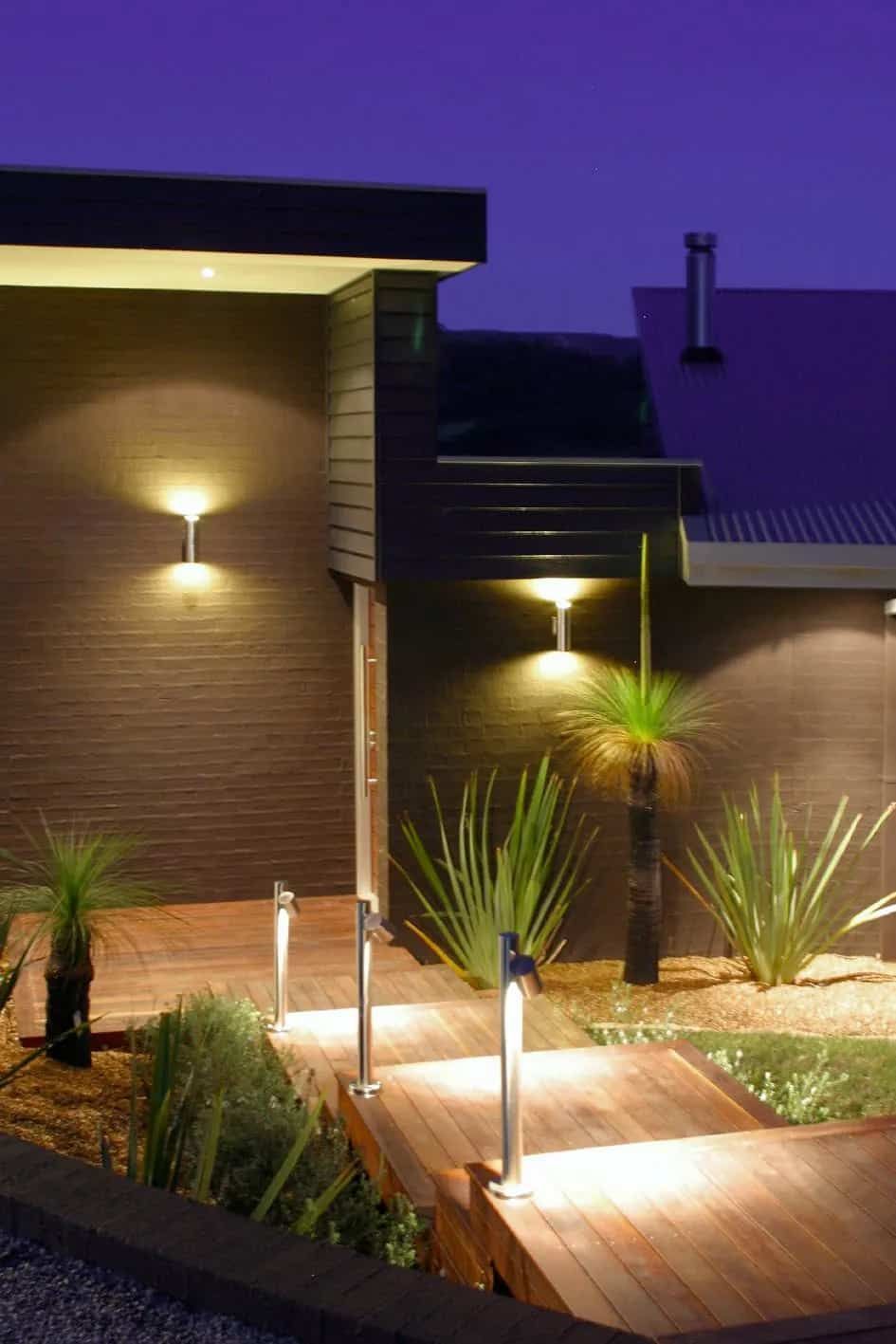 A House With A Wooden Walkway Leading To It Is Lit Up At Night — South Coast Glass In South Nowra, NSW
