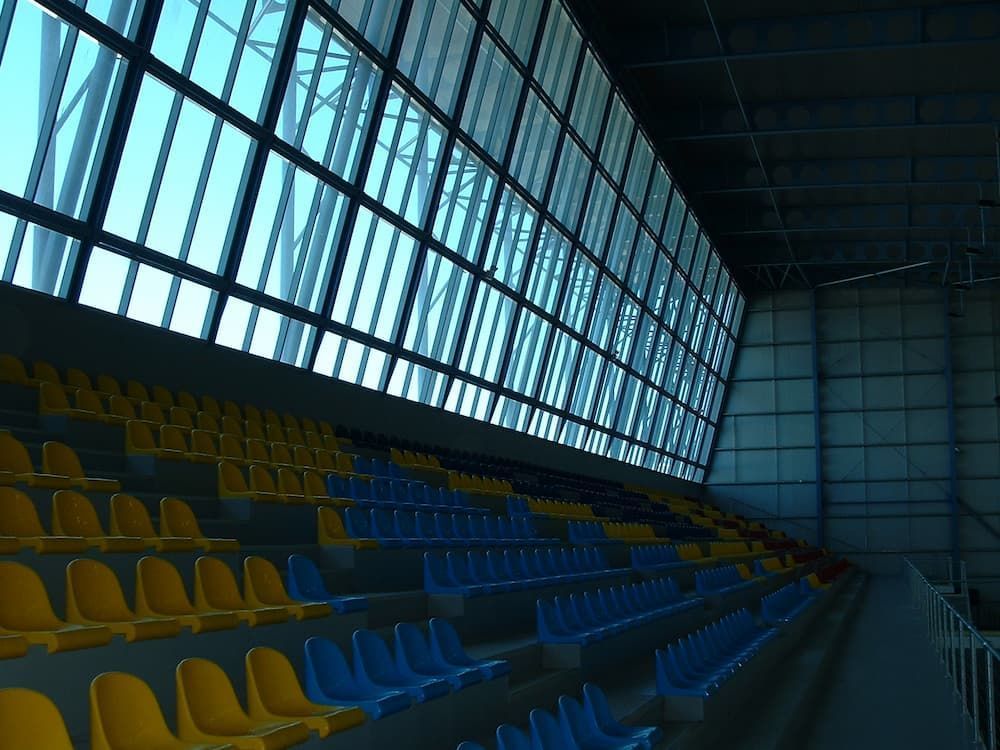 An Empty Stadium With Yellow And Blue Seats And A Large Window — South Coast Glass In South Nowra, NSW