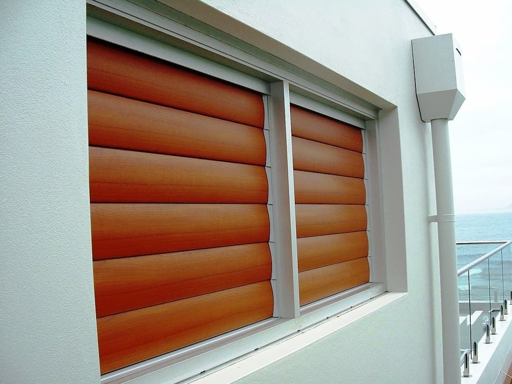 A White Building With A Window With Wooden Blinds On It — South Coast Glass In South Nowra, NSW