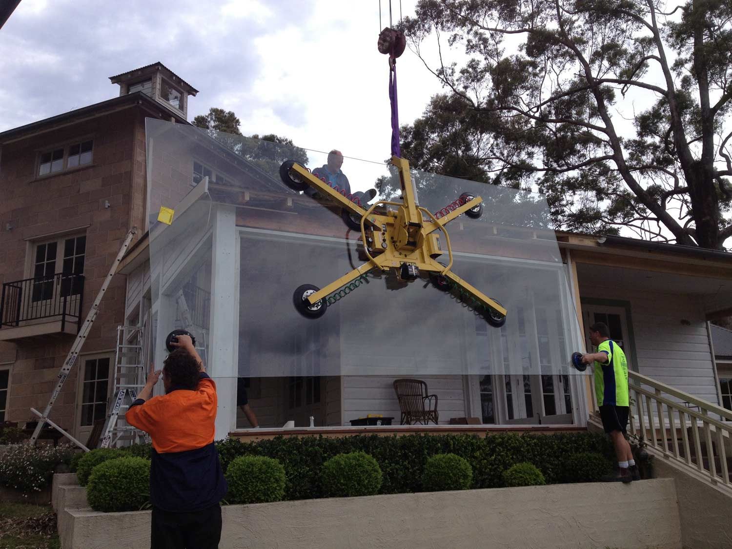 A Crane is Holding Large Piece of Glass Towards the Window Frame — South Coast Glass In South Nowra, NSW