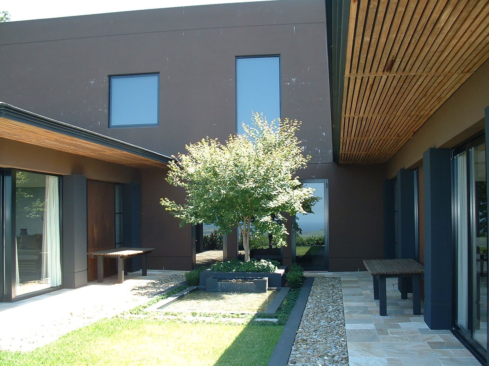 Modern brown building with tree in courtyard, grass, and stone paving — South Coast Glass In South Nowra, NSW