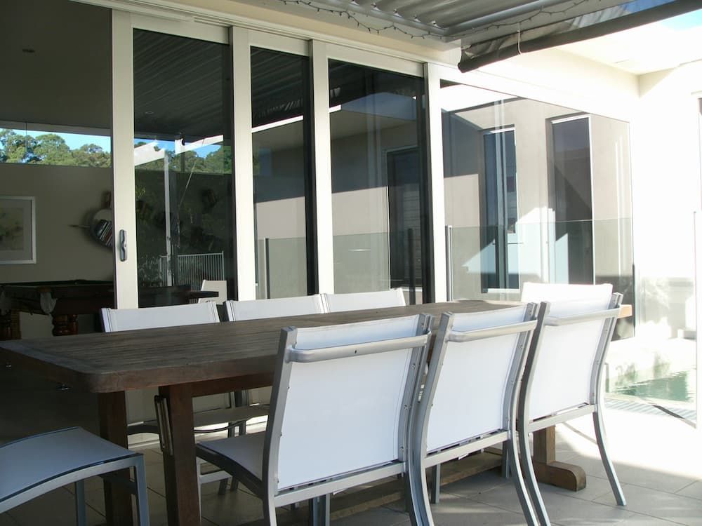A Table And Chairs On A Patio With Sliding Glass Doors — South Coast Glass In South Nowra, NSW