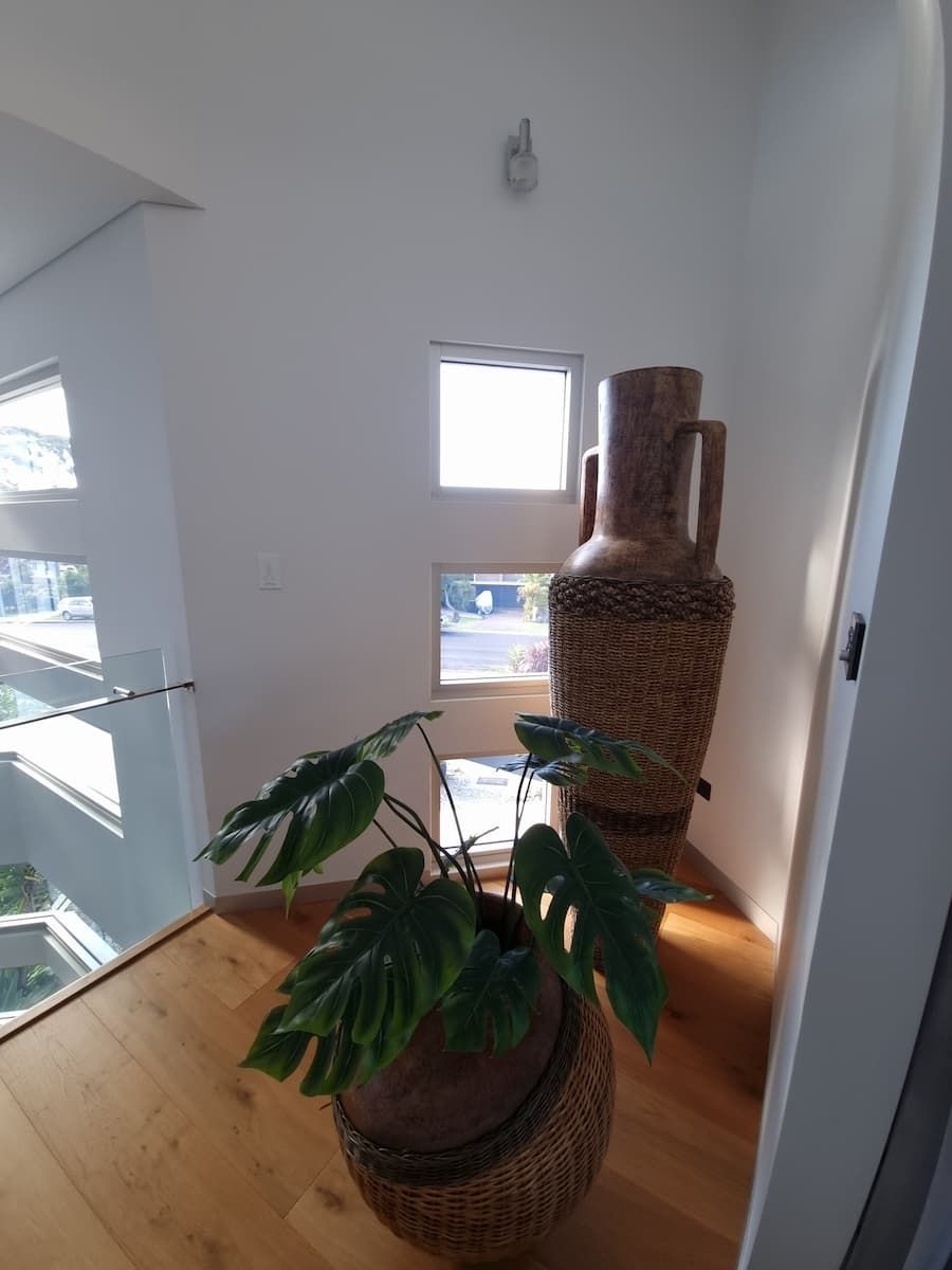 A Potted Plant Is Sitting On A Wooden Table Next To Two Vases — South Coast Glass In South Nowra, NSW