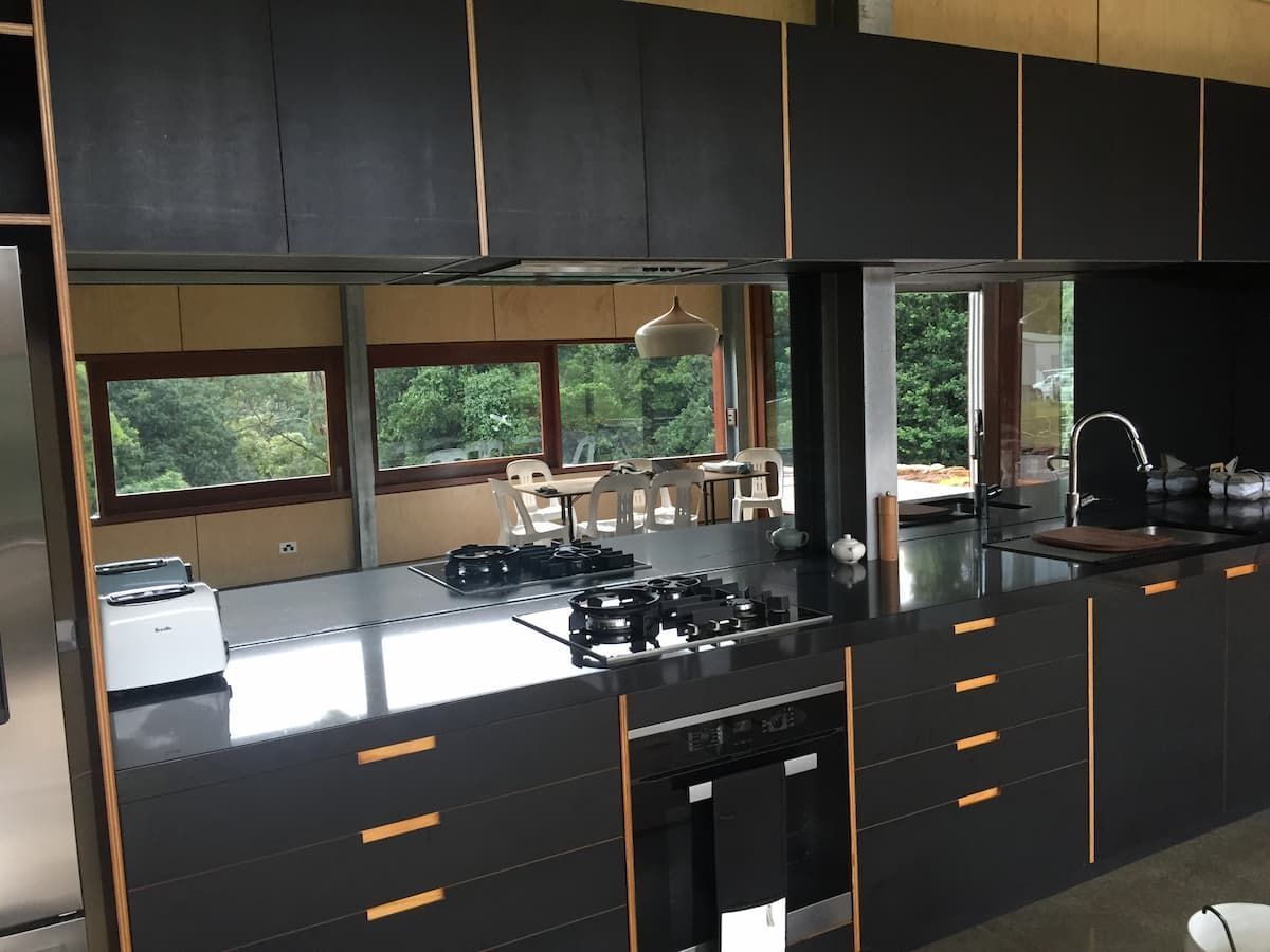 A Kitchen With Black Cabinets And Stainless Steel Appliances — South Coast Glass In South Nowra, NSW