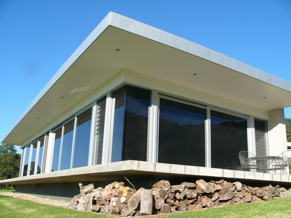 A House With A Lot Of Windows And A Pile Of Logs In Front Of It — South Coast Glass In South Nowra, NSW