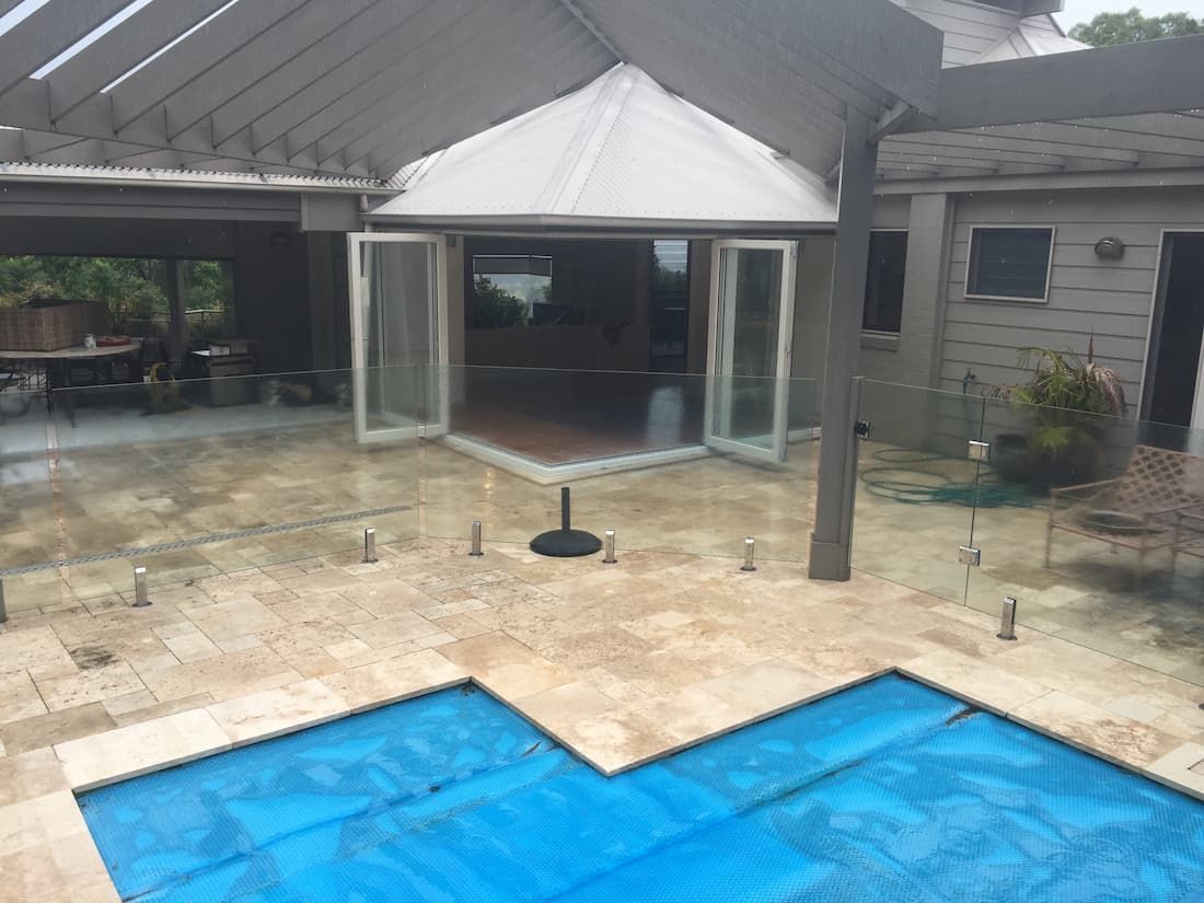 A Swimming Pool With A Blue Cover In Front Of A House — South Coast Glass In South Nowra, NSW