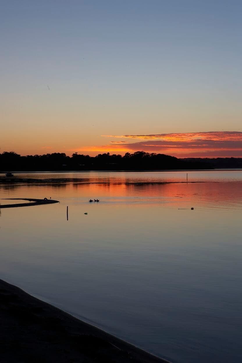 A Large Body Of Water With A Sunset In The Background — South Coast Glass In South Nowra, NSW