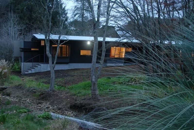 A House Is Surrounded By Trees And Grass And Is Lit Up At Night — South Coast Glass In South Nowra, NSW