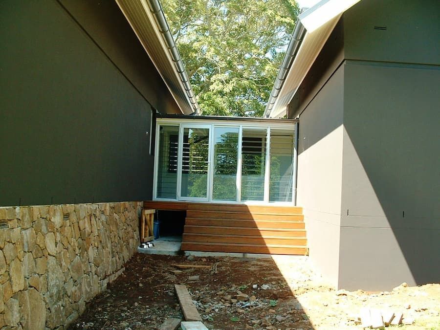 A House With A Lot Of Windows And A Stone Wall — South Coast Glass In South Nowra, NSW
