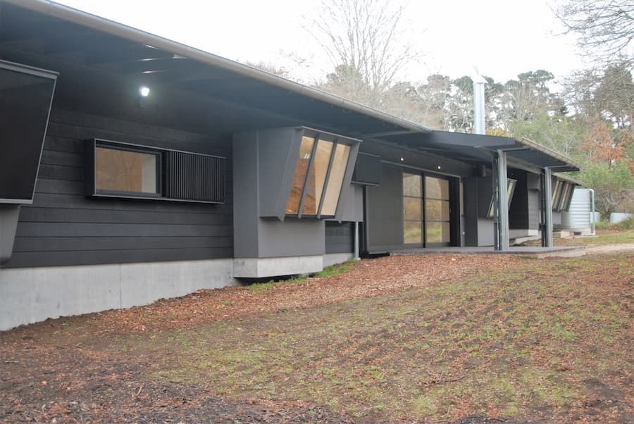 A Large Black House With A Lot Of Windows Is Sitting On Top Of A Grassy Hill — South Coast Glass In South Nowra, NSW