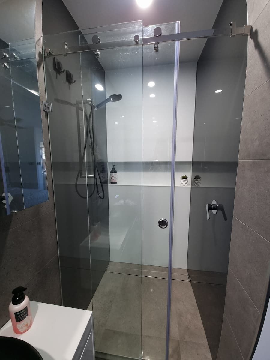 A Bathroom With A Sliding Glass Shower Door And A Sink — South Coast Glass In South Nowra, NSW