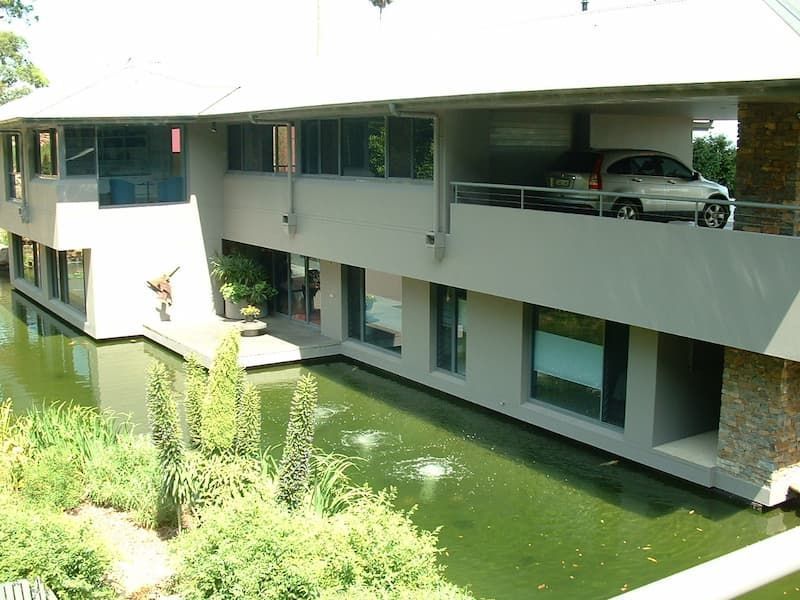 A Car Is Parked Underneath A Building Next To A Pond — South Coast Glass In South Nowra, NSW