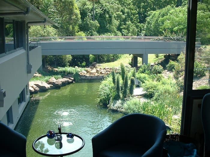 Two Chairs And A Table In Front Of A Pond With A Bridge In The Background — South Coast Glass In South Nowra, NSW