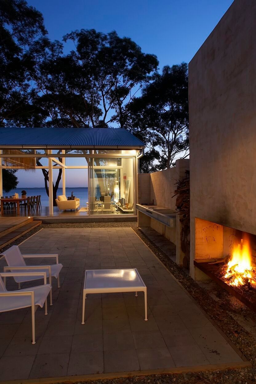 Outdoor patio with fireplace and seating, glass-walled structure overlooking the water at dusk — South Coast Glass In South Nowra, NSW