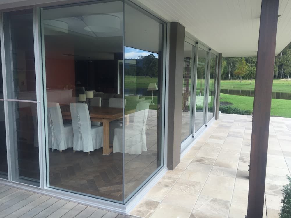 A Dining Room With A Table And Chairs Behind A Glass Wall — South Coast Glass In South Nowra, NSW