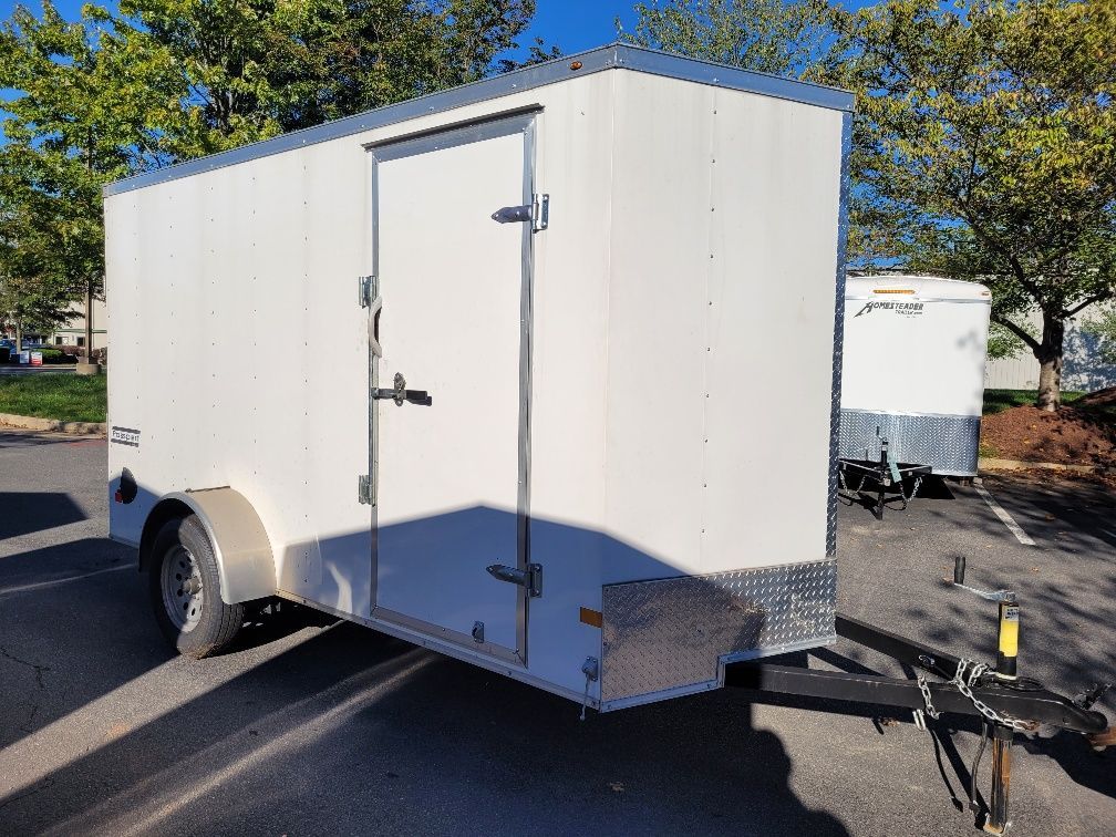 White cargo trailer parked on asphalt; trees in background. | Gainesville Garage & Trailer Sales