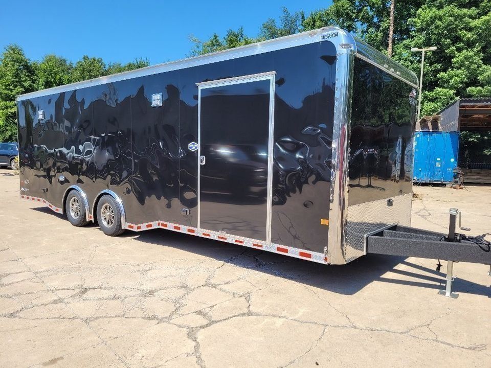 Black enclosed trailer with silver trim parked on pavement. | Gainesville Garage & Trailer Sales