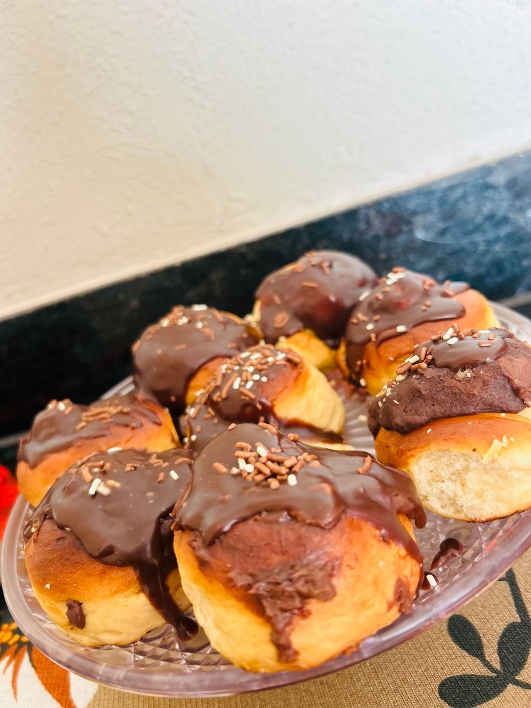Um close de um prato de donuts cobertos de chocolate sobre uma mesa.-Pousada-Morada-dos-Passaros