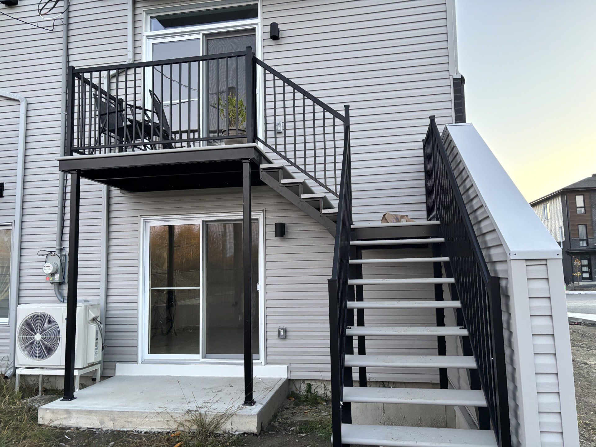 Back patio stairs and balcony on a white brick house with sliding glass doors