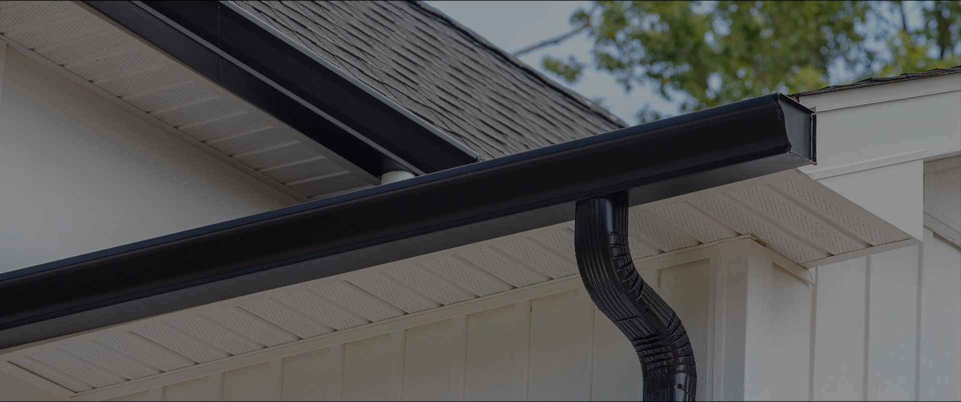 Black gutter and downspout on a white house roofline