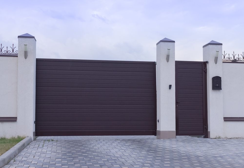 A Brown Sliding Gate is Sitting Next to a White Fence — All Clean Pressure Cleaning in Merewether, NSW