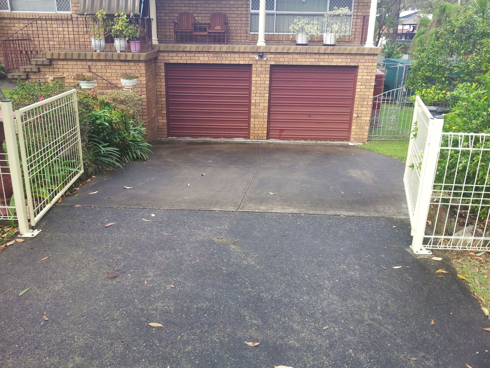 A Driveway Leading to a House With Two Red Garage Doors — All Clean Pressure Cleaning in Valentine, NSW