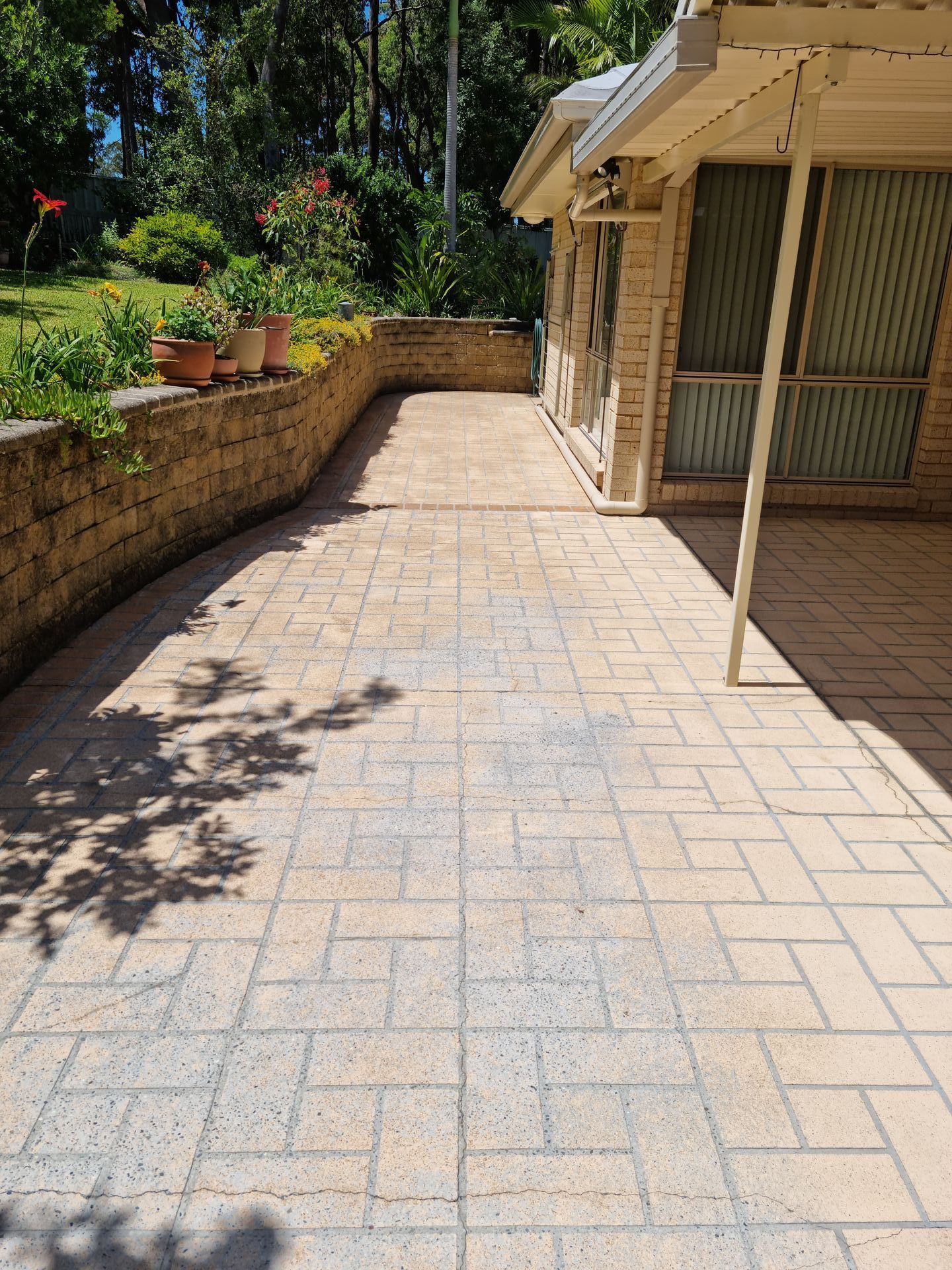 A Brick Walkway Leading to a House With Potted Plants on the Side — All Clean Pressure Cleaning in Valentine, NSW