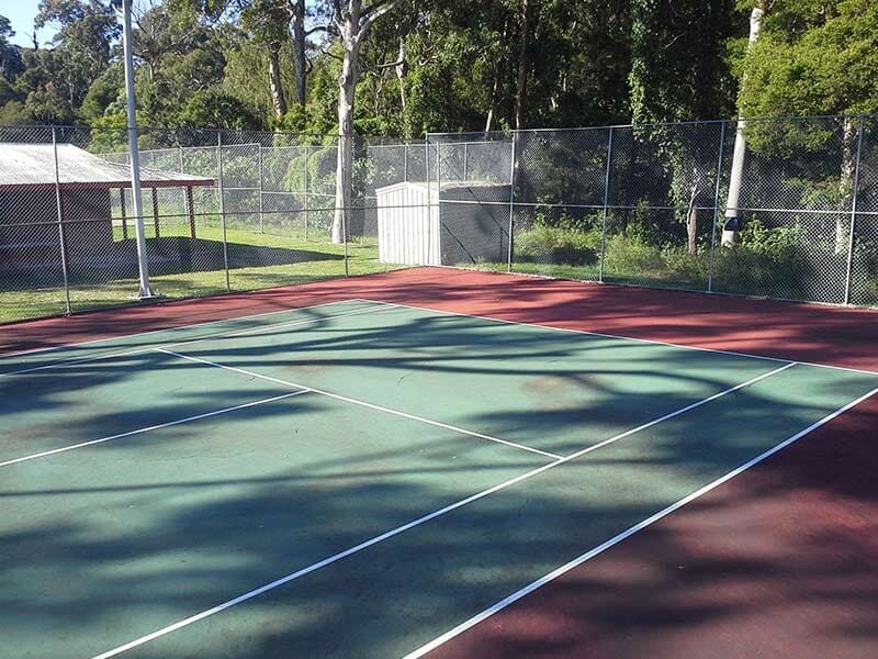 A Tennis Court With a Fence and Trees in the Background — All Clean Pressure Cleaning in Valentine, NSW
