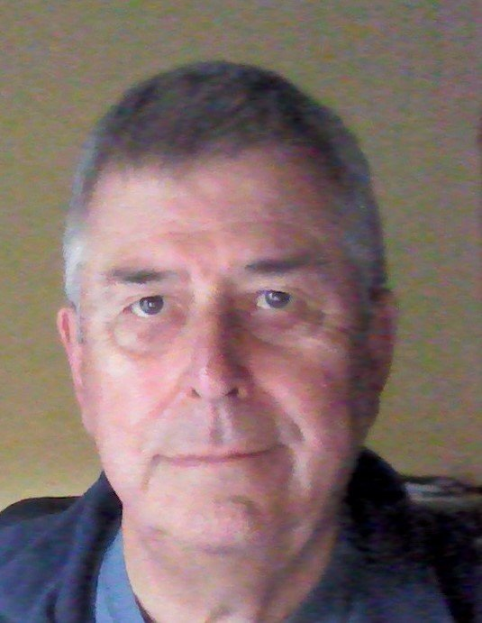 Man with graying hair, blue shirt, looking at the camera.