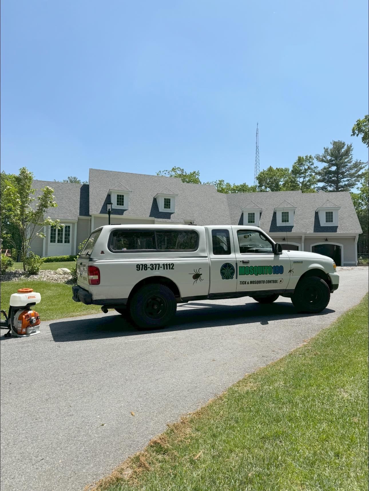 A white truck is parked in front of a large house.