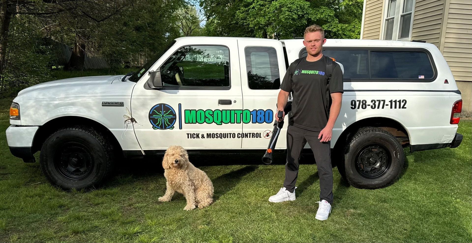 A man and a dog are standing in front of a white truck.