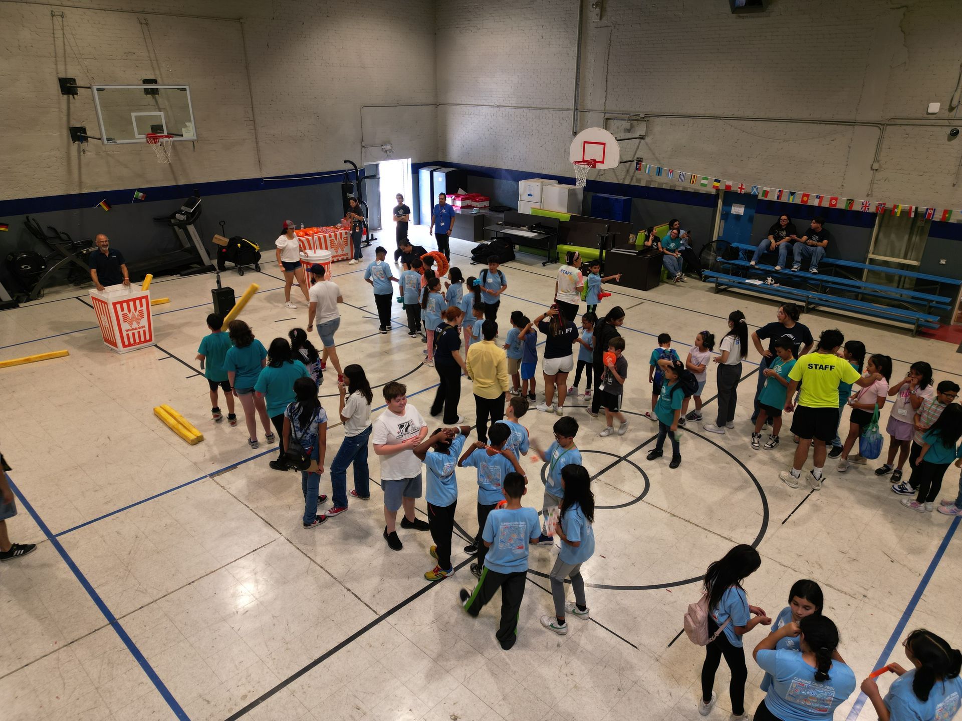 A large group of people are standing in a gym.