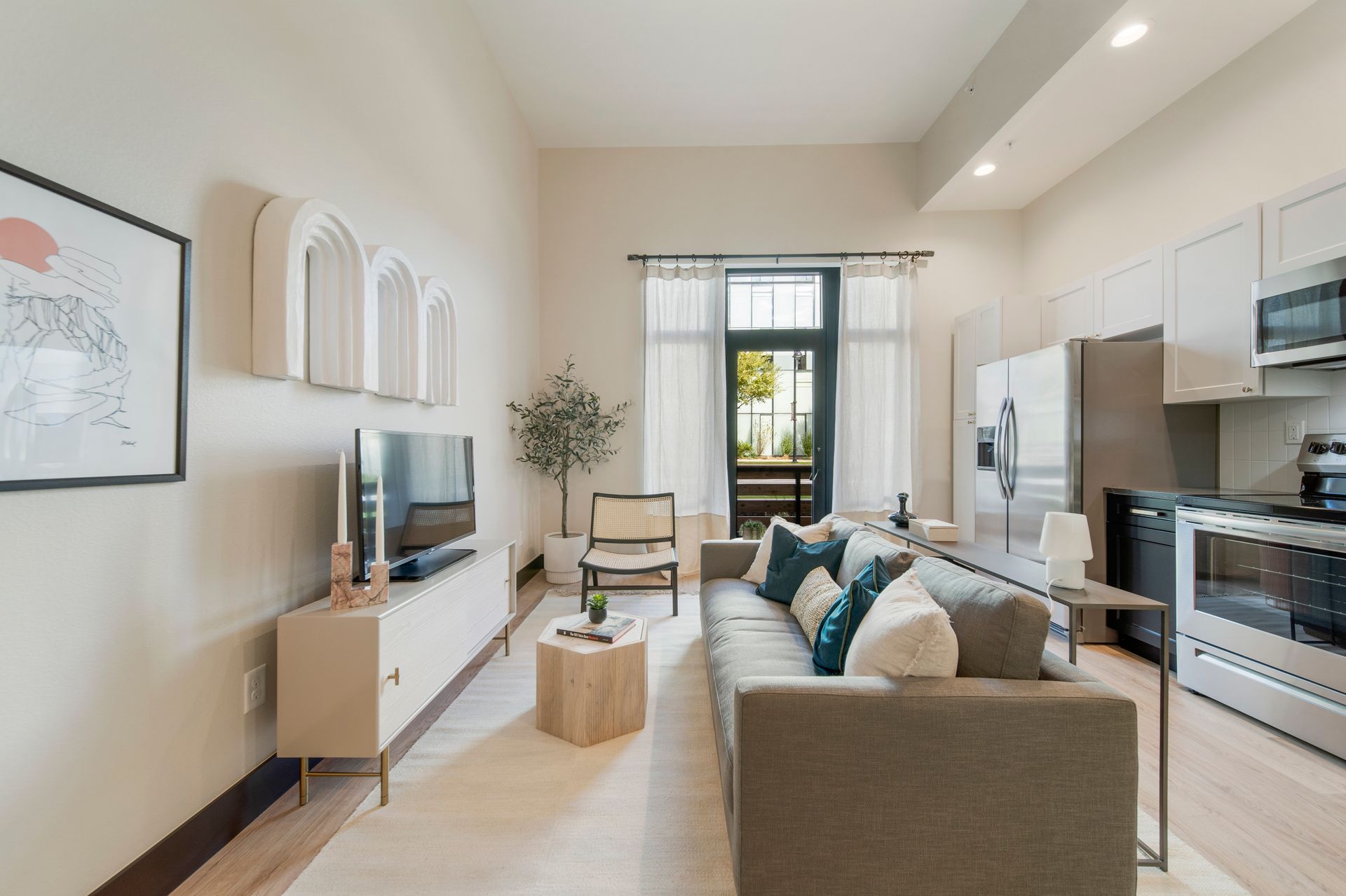 Modern living room with neutral colors, sofa, and open kitchen.