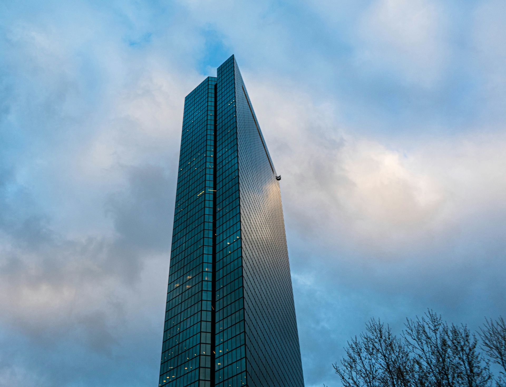 A tall building with a lot of windows is against a cloudy sky.