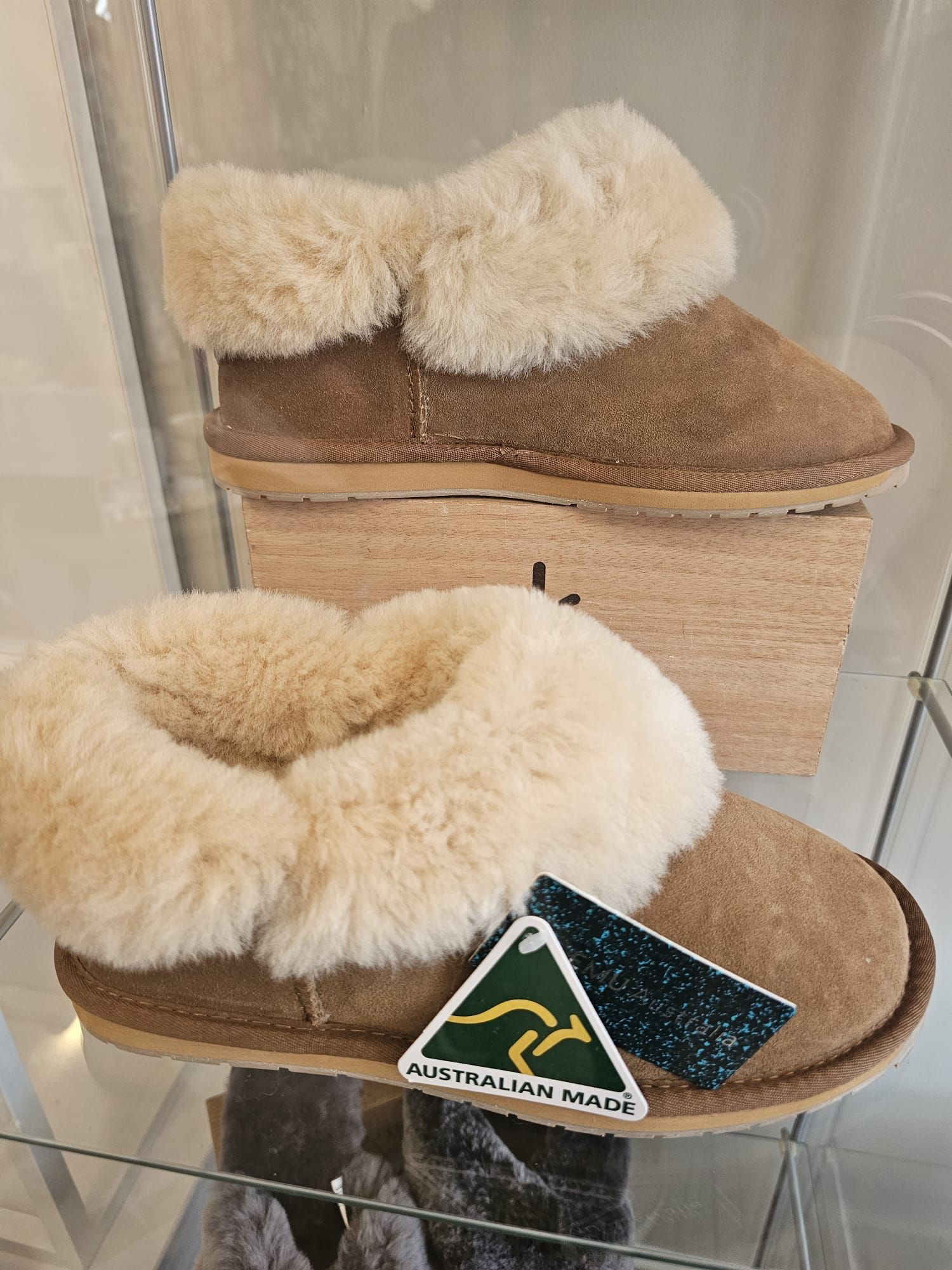 A pair of sheepskin slippers sitting on top of a glass shelf.