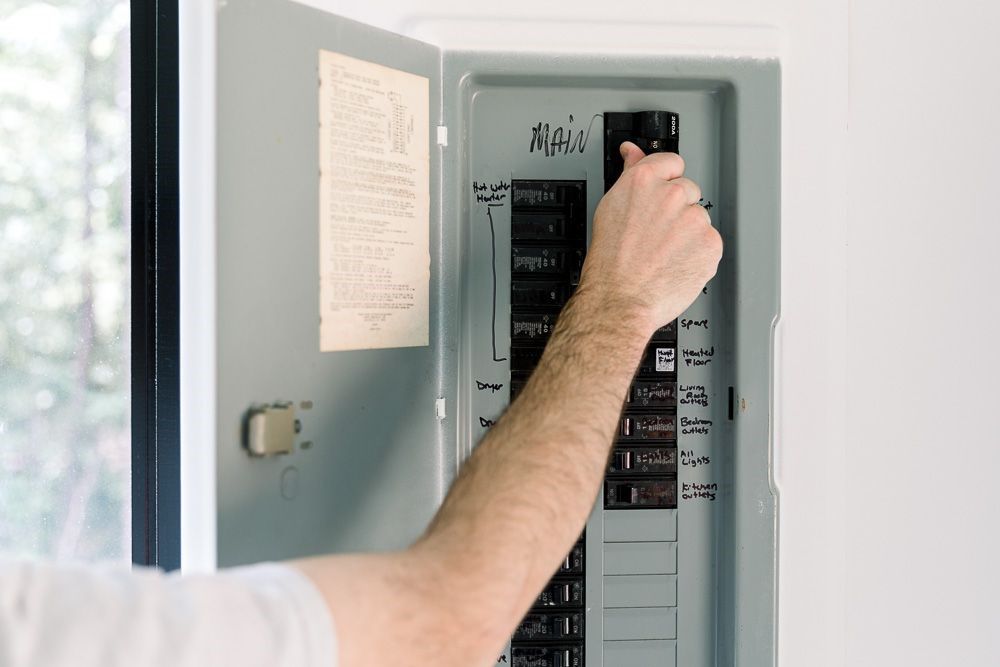 Homeowner resetting a breaker in an open electrical panel