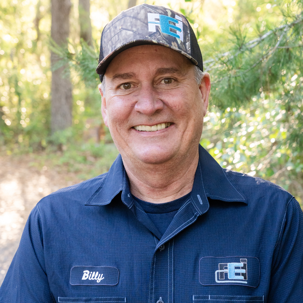 Owner and master electrician Billy Faulkner III is standing and smiling with his Faulkner Electric uniform on.