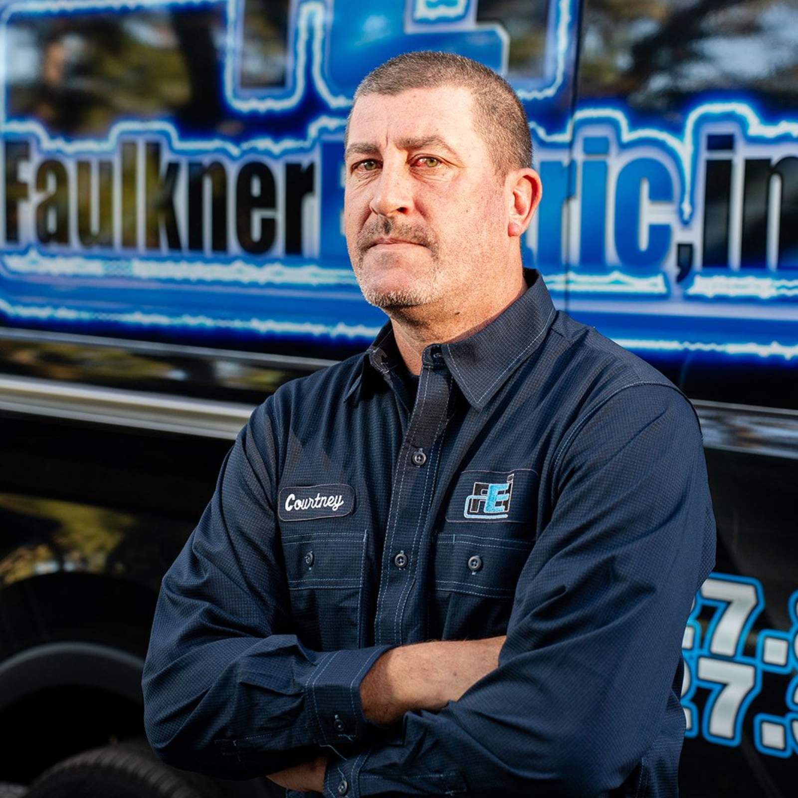 A man is standing in front of a black van.