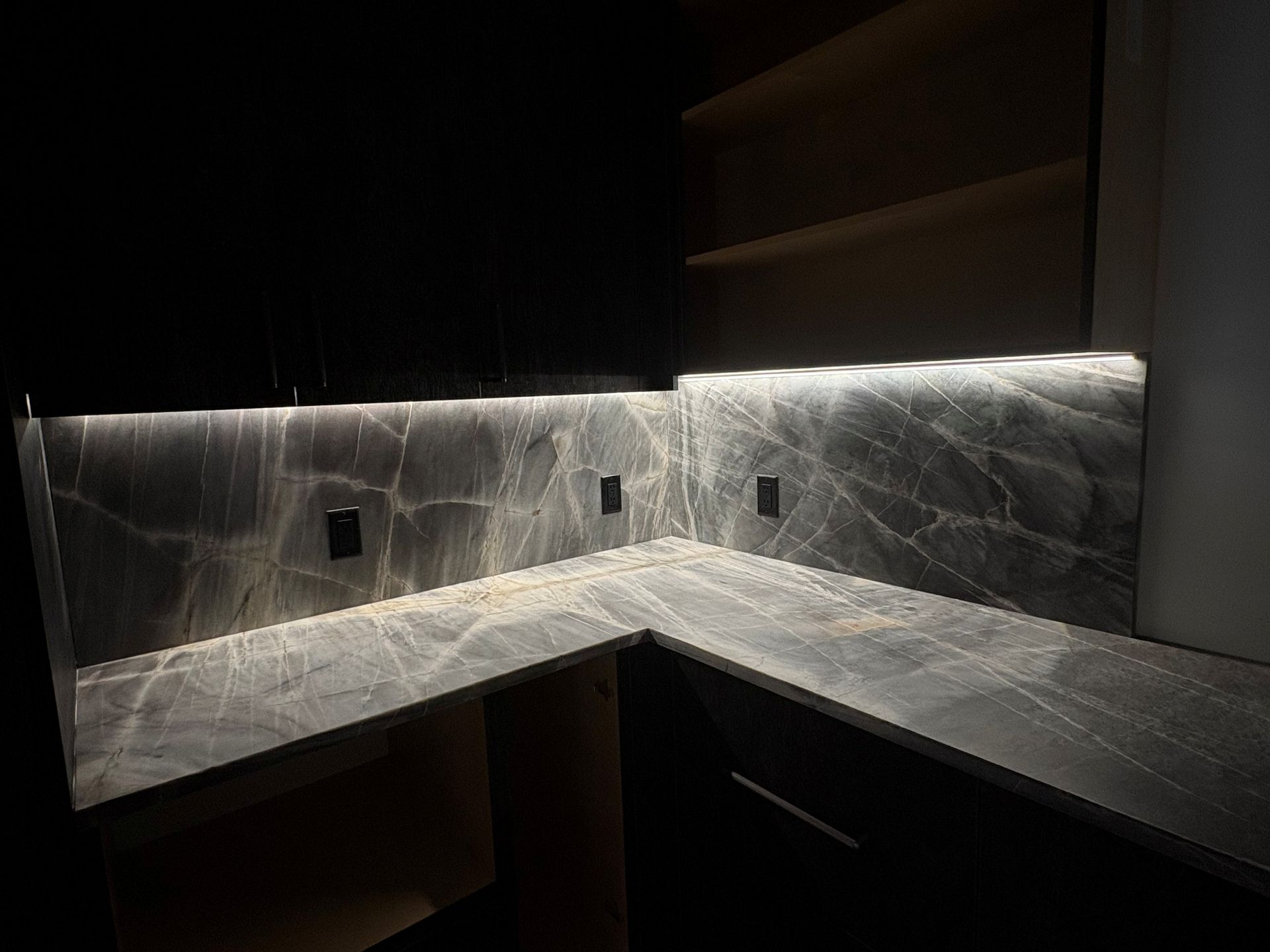 Custom white strip lights installed under kitchen cabinets giving a dramatic lighting