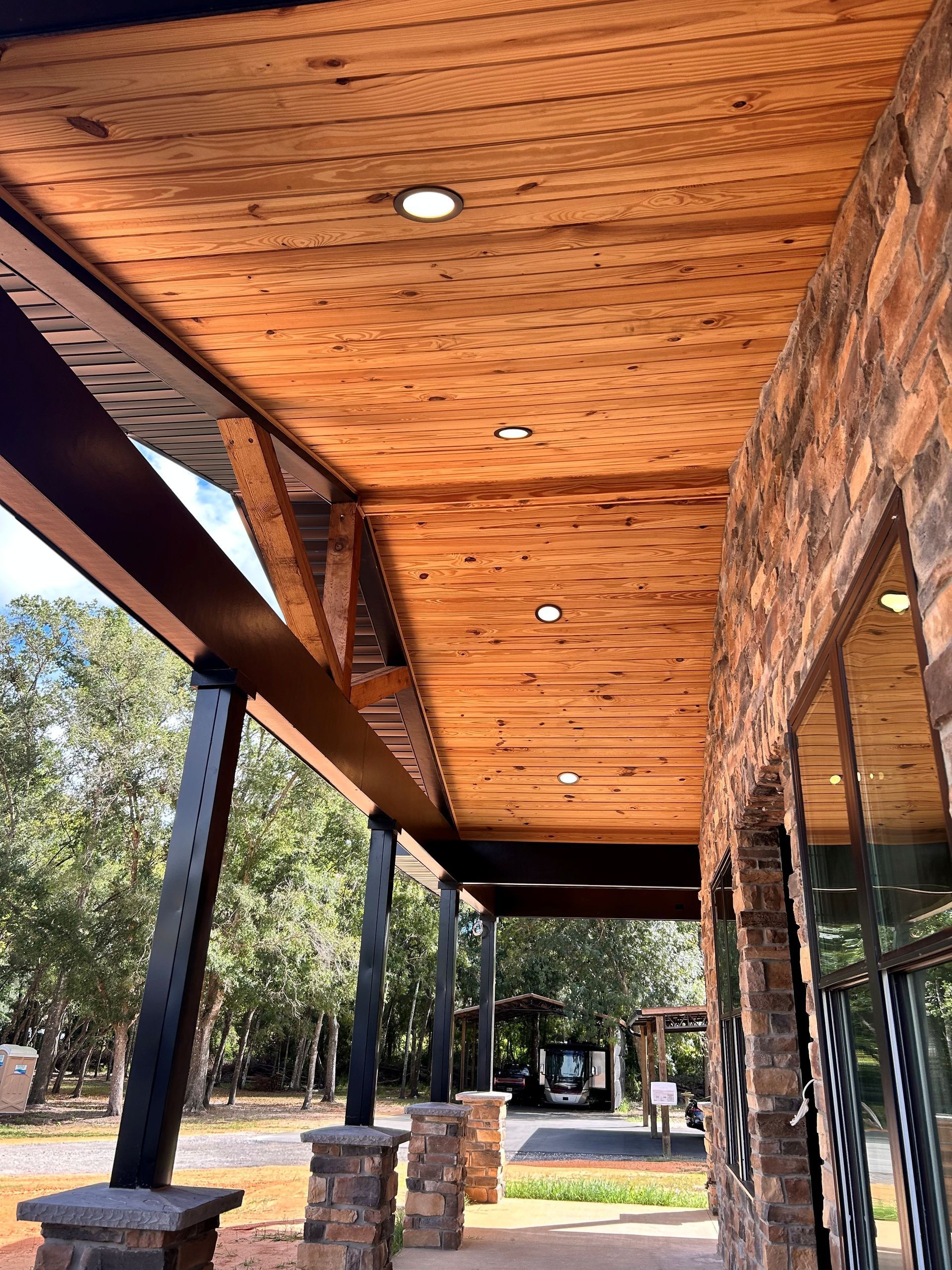 Bright recess lights installed in wood-paneled ceiling for a homes front porch