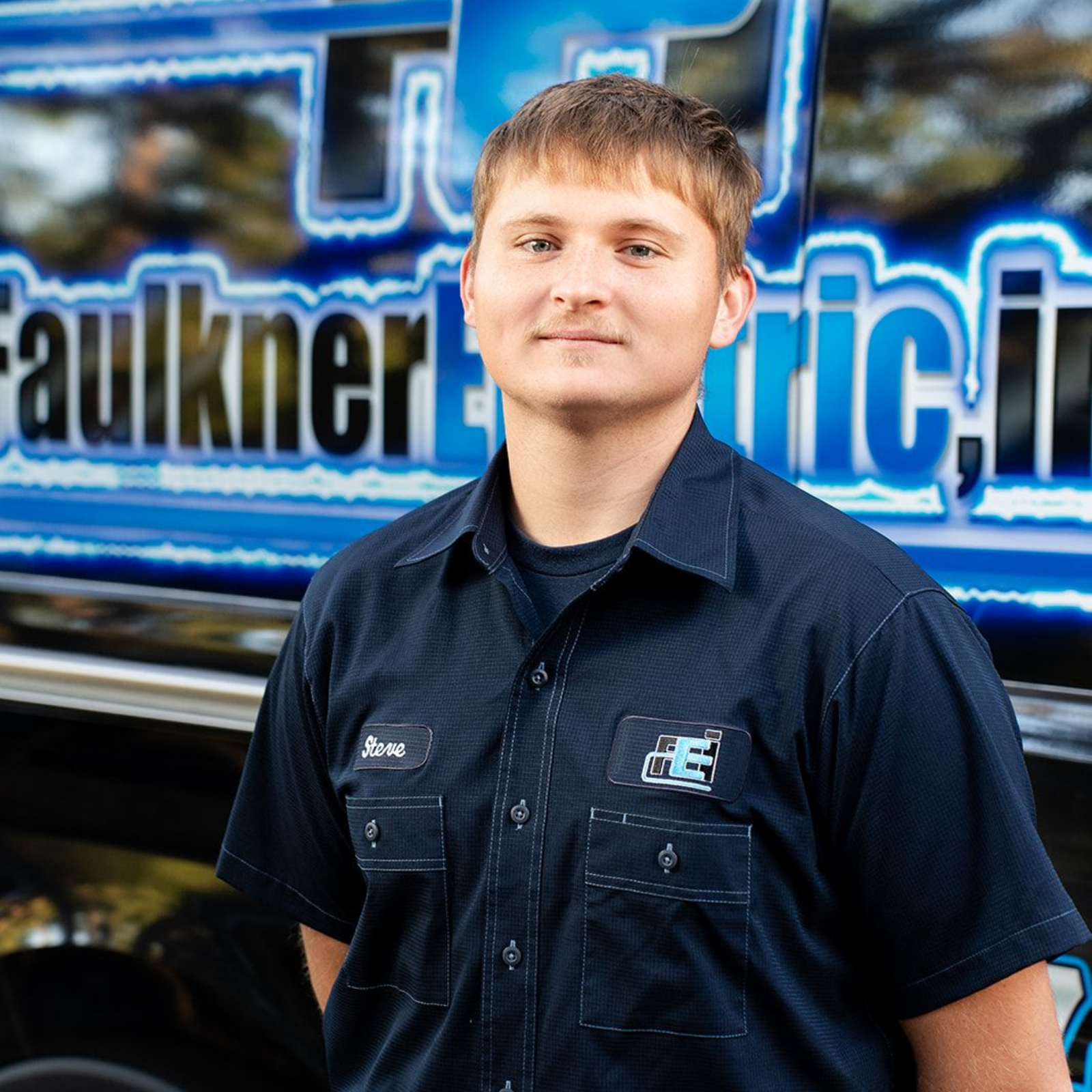 A man is standing in front of a van that says electric inc.