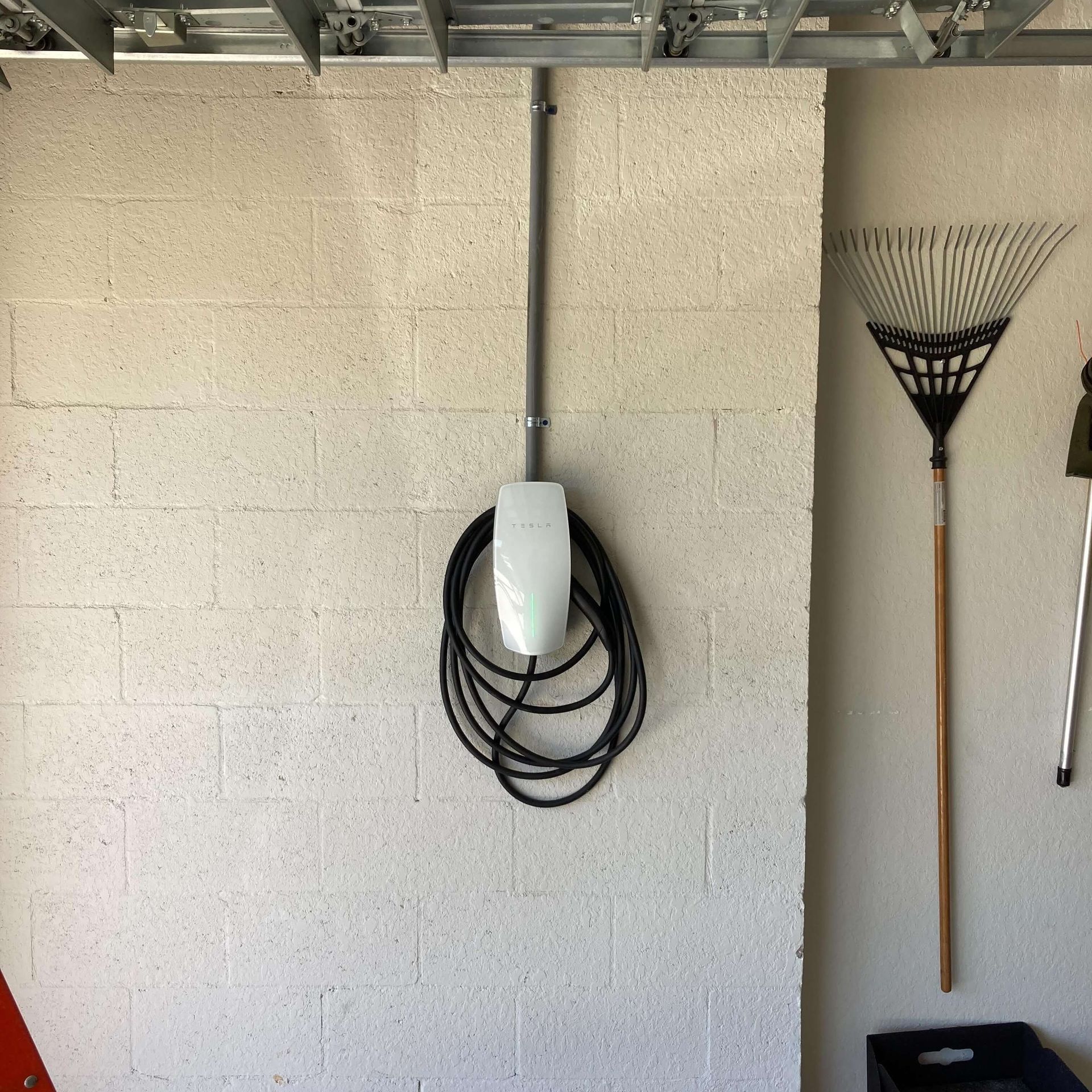 A broom is hanging on a wall next to a hose