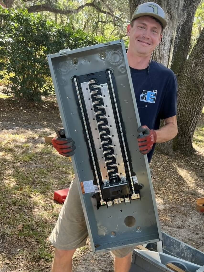 A man is holding a large electrical box in his hands.