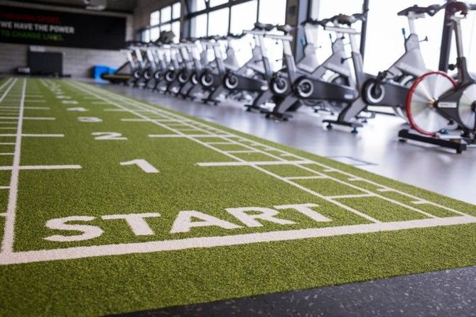 A gym interior featuring a green turf track marked with a