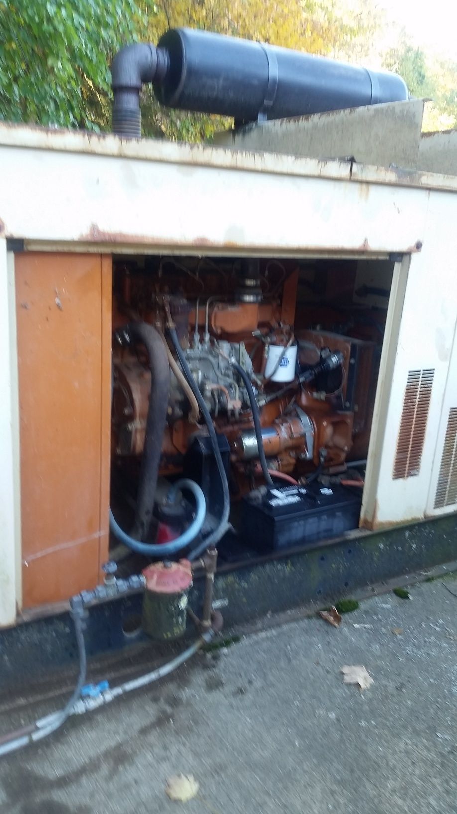 Open generator compartment with exposed engine and piping outside a building