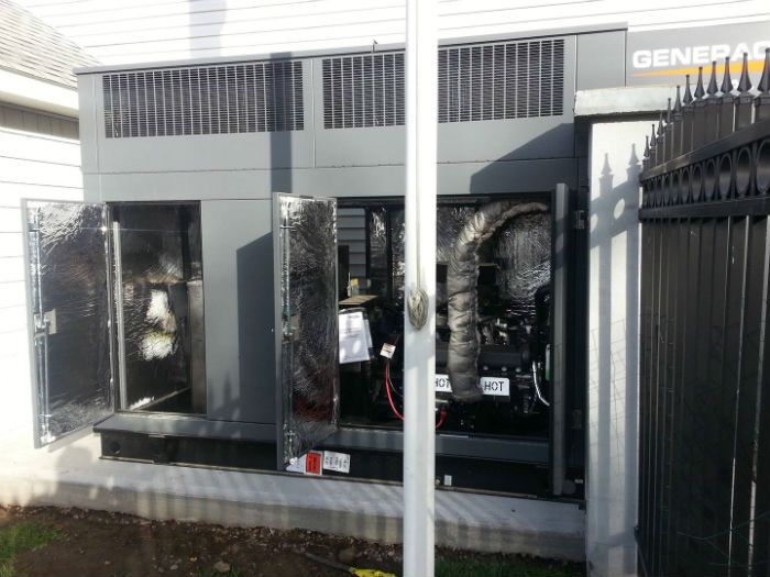 Gray industrial equipment behind black metal fencing outside a building