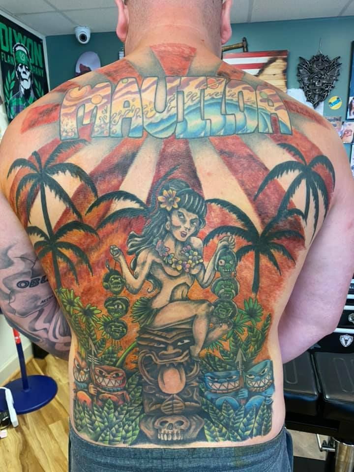 Back tattoo of a colorful tropical scene with palm trees and a seated deity